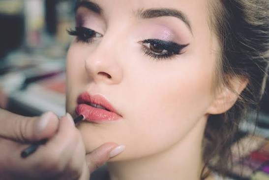 A student applying makeup on the model